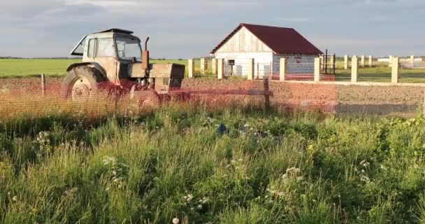 Vieja y oxidada máquina de granja en el campo en el fondo de la casa — Vídeos de Stock