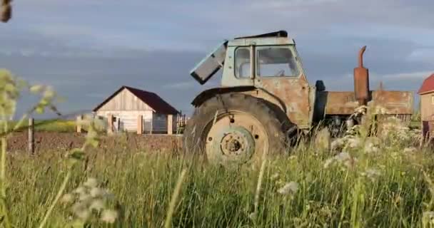 Máquina de fazenda velha e enferrujada no campo no fundo da casa — Vídeo de Stock