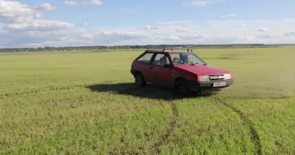 Czerwony samochód jeździ na polu i robi sztuczki — Wideo stockowe
