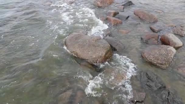Камни и медленное движение воды в море в дневное время — стоковое видео