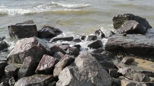 Камни и медленное движение воды в море в дневное время — стоковое видео