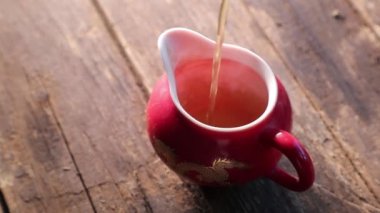 eski bir ahşap masa üzerinde kırmızı bir gaiwan çay dökün