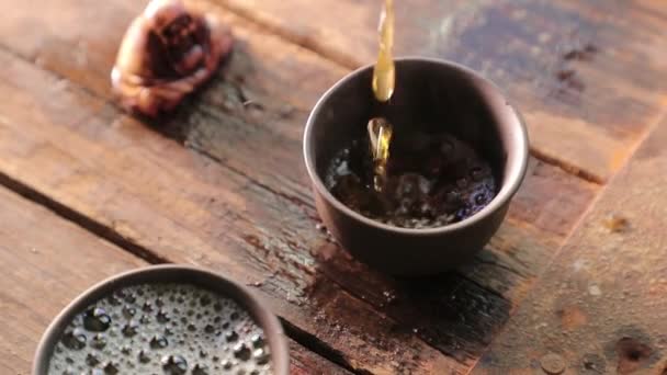 Nalít čaj do malé mísy na dřevěném stole pomalý film — Stock video