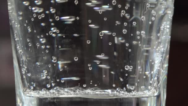 Sauberes, sprudelndes Wasser in einem transparenten Glasbecher aus nächster Nähe — Stockvideo