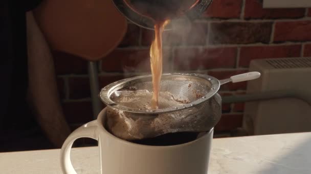 Свіжозварена гаряча ароматизована кава наливається в чашку і фільтрується через сито — стокове відео