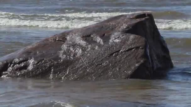 在夏天的风天，海浪冲刷波罗的海岸边的石头 — 图库视频影像