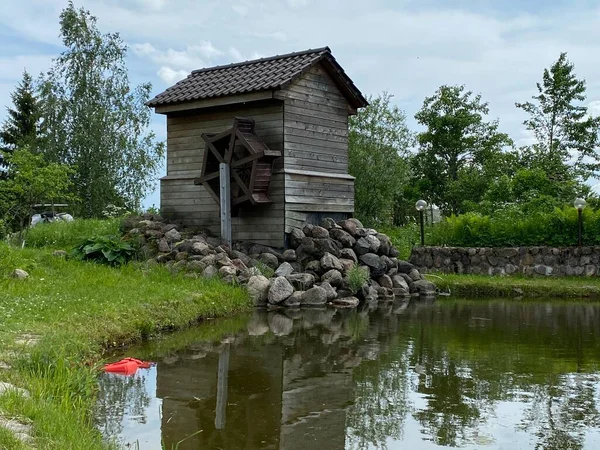 Ancienne maison en bois, une cabane dans un village avec une petite fenêtre est située près d'un étang — Photo