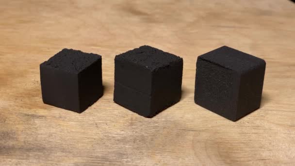 Cubos de carbón vegetal de coco en la mesa de primer plano — Vídeos de Stock
