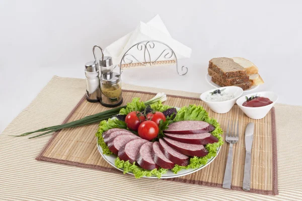 Salám s rajčaty a ledový salát listy na talíři. — Stock fotografie