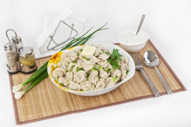 Otlar ve soğan ile Rus köfte. Etli mantı. Tabak bir tabak içinde servis edilir. Köfte ile hizmet ekşi krema bir kabın içinde olduğunu.