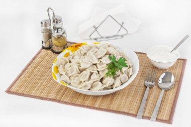 Otlar ve soğan ile Rus köfte. Etli mantı. Tabak bir tabak içinde servis edilir. Köfte ile hizmet ekşi krema bir kabın içinde olduğunu.