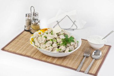 Otlar ve soğan ile Rus köfte. Etli mantı. Tabak bir tabak içinde servis edilir. Köfte ile hizmet ekşi krema bir kabın içinde olduğunu.