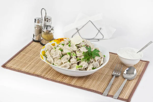 Otlar ve soğan ile Rus köfte. Etli mantı. Tabak bir tabak içinde servis edilir. Köfte ile hizmet ekşi krema bir kabın içinde olduğunu.