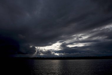 Günbatımı gökyüzü güneş ışınları ve büyük cumulus bulutları bir nehir yukarıda. Kara bulutlar. Thunder Sky.