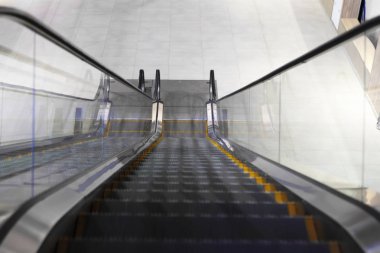 Alışveriş merkezinde merdivensiz yürüyen merdiven. Merdivenlerden iniyorum. Metal platformu kapatın. Üst görünüm.