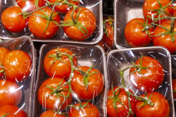 Fresh tomatoes in plastic packaging under a transparent film in the shop window.