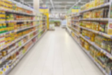 Bulanık fotoğraf. Büyük bir alışveriş merkezi ticaret salonu. Raflar parlak renkli ürünler ile düz satırları.