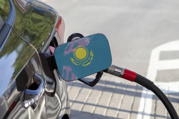 Flag of Kazakstan on the car\'s fuel tank filler flap. Fueling car with petrol pump at a gas station. Petrol station. Gasoline and oil products. Close up.