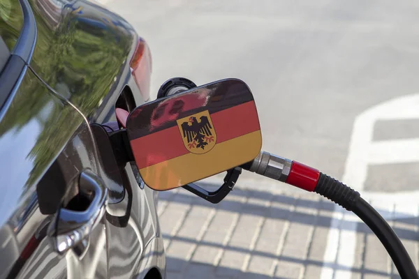 Flag of Germany on the car\'s fuel tank filler flap. Fueling car with petrol pump at a gas station. Petrol station. Gasoline and oil products. Close up.