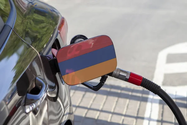 Flag of Armenia on the car\'s fuel tank filler flap. Fueling car with petrol pump at a gas station. Petrol station. Gasoline and oil products. Close up.