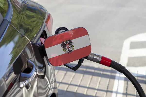 Flag of Austria on the car\'s fuel tank filler flap. Fueling car with petrol pump at a gas station. Petrol station. Gasoline and oil products. Close up.