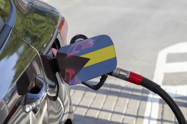 Flag of Bahamas on the car's fuel tank filler flap. Fueling car with petrol pump at a gas station. Petrol station. Gasoline and oil products. Close up.
