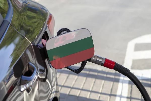 Flag of Bulgaria on the car\'s fuel tank filler flap. Fueling car with petrol pump at a gas station. Petrol station. Gasoline and oil products. Close up.