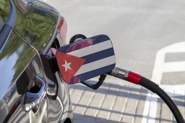Flag of Cuba on the car\'s fuel tank filler flap. Fueling car with petrol pump at a gas station. Petrol station. Gasoline and oil products. Close up.
