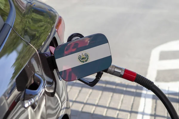 Flag of El Slvador on the car\'s fuel tank filler flap. Fueling car with petrol pump at a gas station. Petrol station. Gasoline and oil products. Close up.