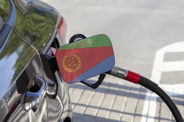 Flag of Eritrea on the car\'s fuel tank filler flap. Fueling car with petrol pump at a gas station. Petrol station. Gasoline and oil products. Close up.