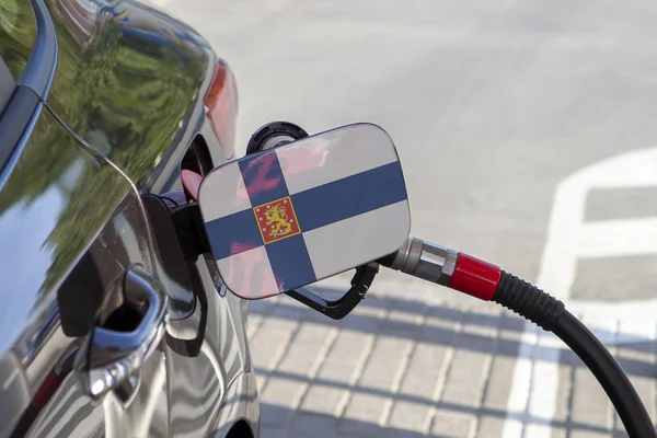 Flag of Finland on the car\'s fuel tank filler flap. Fueling car with petrol pump at a gas station. Petrol station. Gasoline and oil products. Close up.