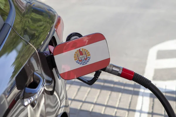 Flag of French Polynesia on the car\'s fuel tank filler flap. Fueling car with petrol pump at a gas station. Petrol station. Gasoline and oil products. Close up.