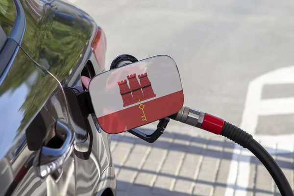 Flag of Gibraltar on the car\'s fuel tank filler flap. Fueling car with petrol pump at a gas station. Petrol station. Gasoline and oil products. Close up.