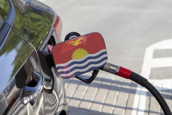Flag of Kiribati on the car's fuel tank filler flap. Fueling car with petrol pump at a gas station. Petrol station. Gasoline and oil products. Close up.