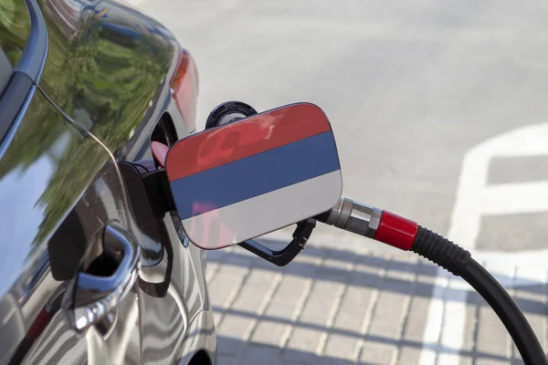 Flag of Montenegro on the car's fuel tank filler flap. Fueling car with petrol pump at a gas station. Petrol station. Gasoline and oil products. Close up.