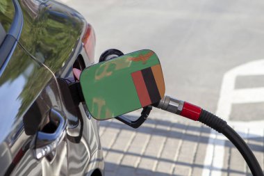 Otomobilin yakıt tankı dolgu Zambiya bayrağı çırpın. Yakıt araba benzin istasyonunda benzin pompası ile. Benzin istasyonu. Benzin ve petrol ürünleri. Yakın çekim.
