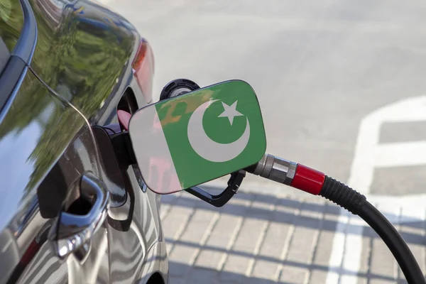 Flag of Pakistan on the car\'s fuel tank filler flap. Fueling car with petrol pump at a gas station. Petrol station. Gasoline and oil products. Close up.