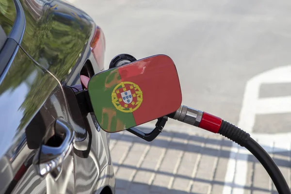 Flag of Portugal on the car\'s fuel tank filler flap. Fueling car with petrol pump at a gas station. Petrol station. Gasoline and oil products. Close up.