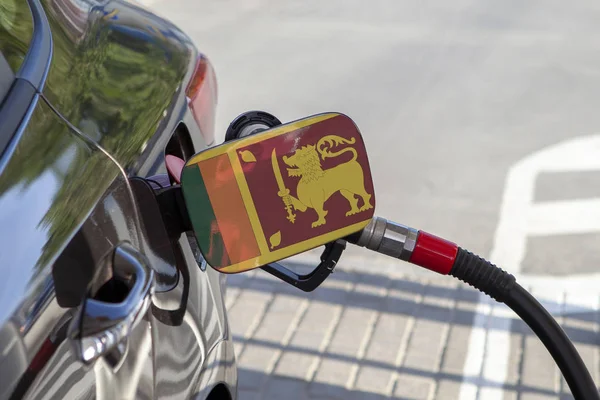 Flag of Sri Lanka on the car\'s fuel tank filler flap. Fueling car with petrol pump at a gas station. Petrol station. Gasoline and oil products. Close up.