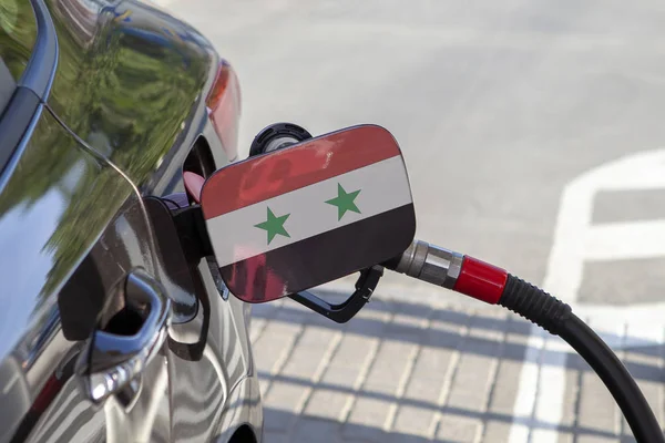 Flag of Syria on the car\'s fuel tank filler flap. Fueling car with petrol pump at a gas station. Petrol station. Gasoline and oil products. Close up.