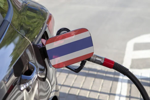 Flag of Thailande on the car\'s fuel tank filler flap. Fueling car with petrol pump at a gas station. Petrol station. Gasoline and oil products. Close up.