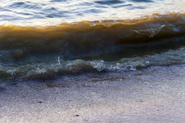 Dalgalar büyük bir nehir kıyısında kumlu. Işık ışınları dalgalar halinde yansıtılır,