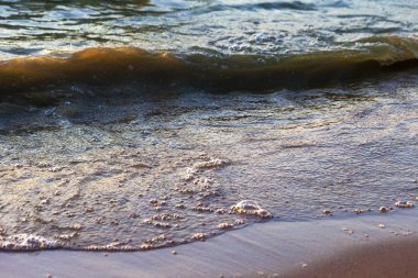 Dalgalar büyük bir nehir kıyısında kumlu. Işık ışınları dalgalar halinde yansıtılır,