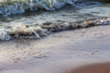 Dalgalar büyük bir nehir kıyısında kumlu. Işık ışınları dalgalar halinde yansıtılır,