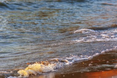 Dalgalar büyük bir nehir kıyısında kumlu. Işık ışınları dalgalar halinde yansıtılır,