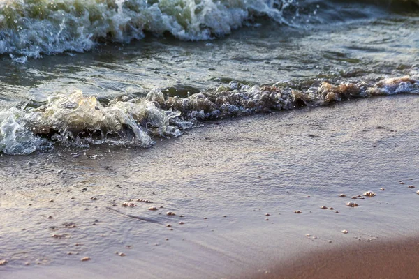 Dalgalar büyük bir nehir kıyısında kumlu. Işık ışınları dalgalar halinde yansıtılır,