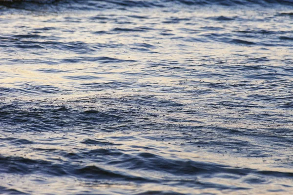 Dalgalar büyük bir nehir kıyısında kumlu. Işık ışınları dalgalar halinde yansıtılır,