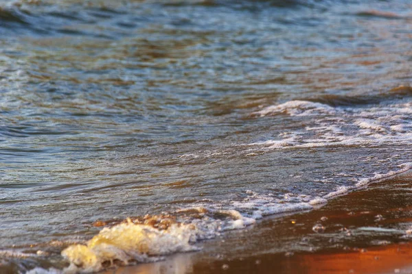 Dalgalar büyük bir nehir kıyısında kumlu. Işık ışınları dalgalar halinde yansıtılır,