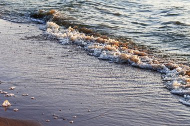 Dalgalar büyük bir nehir kıyısında kumlu. Işık ışınları dalgalar halinde yansıtılır,