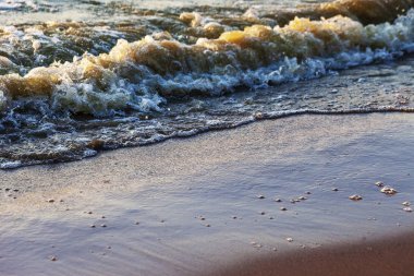 Dalgalar büyük bir nehir kıyısında kumlu. Işık ışınları dalgalar halinde yansıtılır,